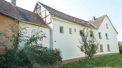 Zwangsversteigerung Einfamilienhaus in Alheim, Heinebach – Rückwärtige Gebäudeansicht mit angebauter Scheune und Hofmauer.