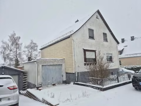 Zwangsversteigerung Einfamilienhaus in Bad Endbach, Bottenhorn – Seitenansicht des Wohngebäudes mit links angebauter Garage.