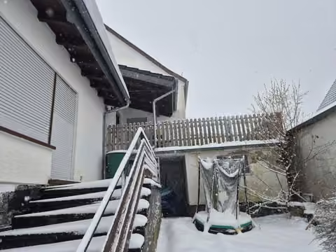 Zwangsversteigerung Einfamilienhaus in Bad Endbach, Bottenhorn – Rückseite mit Treppenaufgang und überdachter Terrasse.