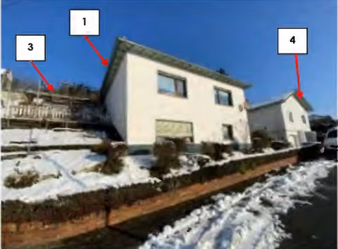 Zwangsversteigerung in Solms, Oberbiel – Vorderansicht des freistehenden Wohnhauses mit Anbau und Hanglage im Schnee.