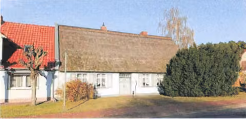 Zwangsversteigerung Gewerbe in Korswandt, Ulrichshorst – Straßenseitige Außenansicht des reetgedeckten Bauernhauses mit Schmuckfassade.