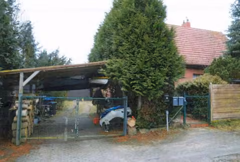 Zwangsversteigerung Einfamilienhaus in Grambow, Schwennenz – Außenansicht des Grundstücks mit Zufahrt, Carport und Wohnhaus im Hintergrund.