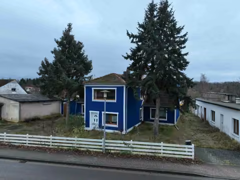 Zwangsversteigerung in Ueckermünde, Bellin – Straßenseitige Außenansicht des Ferienwohnhauses mit markantem blauem Torbogen und Fassadendetails.