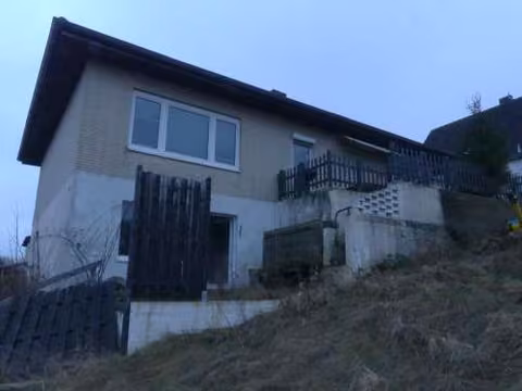Zwangsversteigerung Einfamilienhaus in Salzgitter, Gitter – Nordwestansicht mit Hanggeschoss und Terrassenbereich.