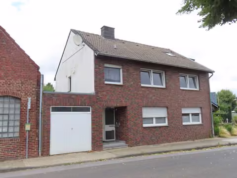 Zwangsversteigerung Einfamilienhaus in Titz, Hasselsweiler – Straßenansicht des Einfamilienhauses mit Garage und Klinkerfassade.