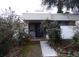 Zwangsversteigerung Einfamilienhaus in Bergisch Gladbach, Herkenrath – Außenansicht des Flachdachbungalows von Nordosten mit Eingangsbereich.