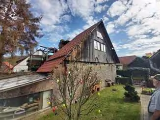 Zwangsversteigerung Einfamilienhaus in Höxter, Ovenhausen – Westliche Giebelseite aus Bruchsteinmauerwerk mit rückwärtigem Anbau und Gartengrundstück.