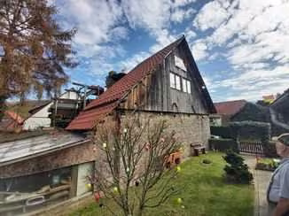 Zwangsversteigerung Einfamilienhaus in Höxter, Ovenhausen – Westliche Giebelseite aus Bruchsteinmauerwerk mit rückwärtigem Anbau und Gartengrundstück.