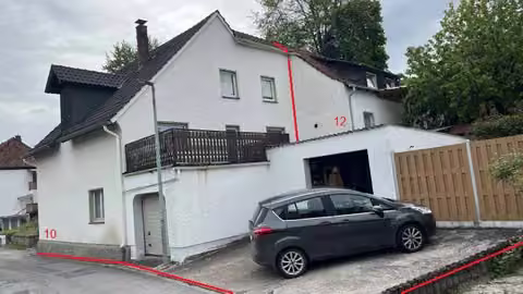 Zwangsversteigerung Doppelhaushälfte in Beverungen, Dalhausen – Außenansicht von Nord-Osten mit Doppelhaushälfte und angegliederter Garagenbebauung.