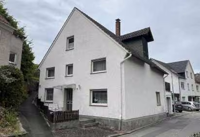 Zwangsversteigerung Doppelhaushälfte in Beverungen, Dalhausen – Südliche Giebelseite des Wohnhauses an der ansteigenden Ringstraße.