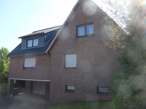 Zwangsversteigerung Einfamilienhaus in Porta Westfalica, Nammen – Giebelseite mit Garagenunterfahrt und Hanglage.