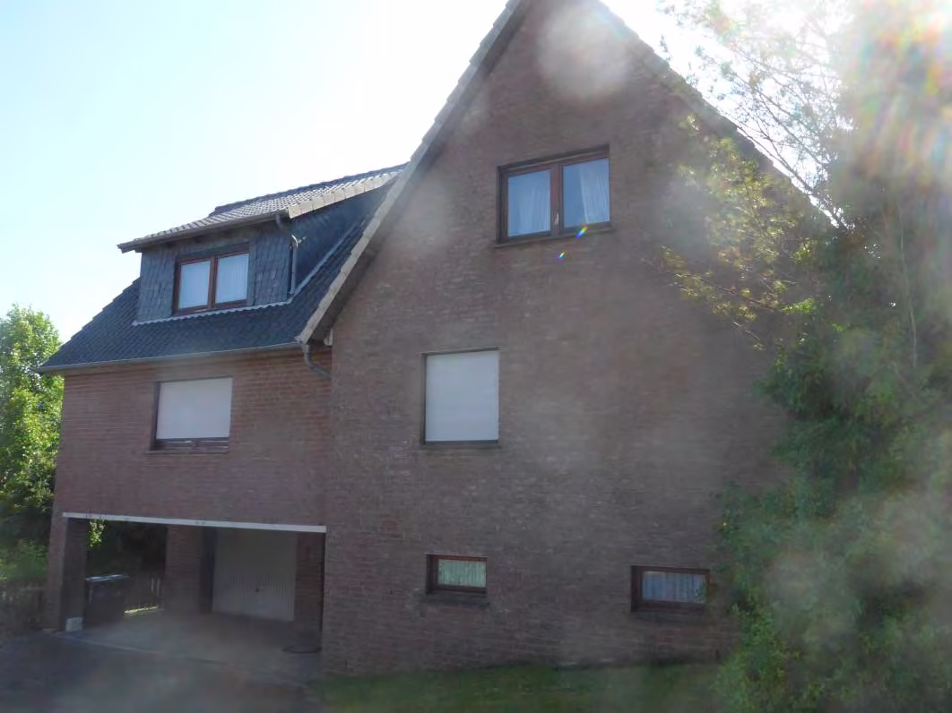 Zwangsversteigerung Einfamilienhaus in Porta Westfalica, Nammen – Giebelseite mit Garagenunterfahrt und Hanglage.