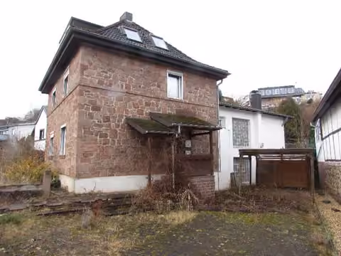 Zwangsversteigerung Zweifamilienhaus in Nideggen, Abenden – Außenansicht der Straßenfront mit Buntsandsteinfassade des Altbaus und Zufahrtsbereich.