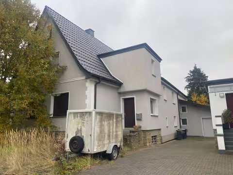 Zwangsversteigerung Einfamilienhaus in Lage – Vorderansicht des Wohnhauses mit Hofeinfahrt und Eingangsbereich.