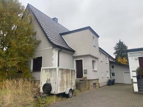 Zwangsversteigerung Einfamilienhaus in Lage – Westansicht des Wohngebäudes mit Grundstücksgrenze.