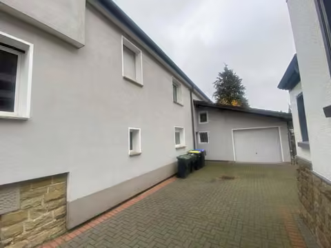 Zwangsversteigerung Einfamilienhaus in Lage – Hofeinfahrt und Anbau mit unmittelbarem Übergang zur Nachbargarage.