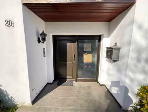 Zwangsversteigerung Einfamilienhaus in Rheurdt, Schaephuysen – Überdachter Hauseingangsbereich des Bungalows von der Straße aus gesehen.