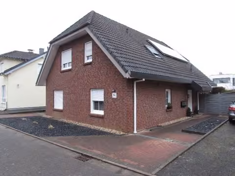 Zwangsversteigerung Zweifamilienhaus in Pulheim – Frontansicht des verklinkerten Zweifamilienhauses mit Hauseingang und Stellplatzbereich.