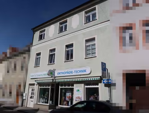 Zwangsversteigerung Eigentumswohnung in Großenhain – Schrägansicht der Straßenfassade mit Gewerbeeinheit im Erdgeschoss.