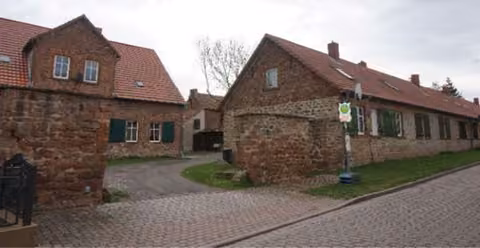 Zwangsversteigerung Mehrfamilienhaus in Hohe Börde, Schackensleben – Straßenansicht der denkmalgeschützten Wohnanlage aus südwestlicher Richtung.
