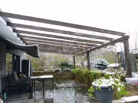 Zwangsversteigerung Reihenhaus in Werl – Eingefasste Terrasse mit Pergola und Markise.