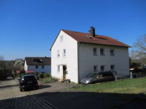 Zwangsversteigerung Einfamilienhaus in Igensdorf, Unterrüsselbach – Außenansicht des Wohnhauses mit Garage von der Zufahrt aus gesehen.