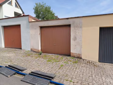 Zwangsversteigerung Stellplatz/Garage in Gochsheim, Weyer – Außenansicht der PKW-Reihenmittelgarage mit Schwingtor und gepflastertem Vorplatz.