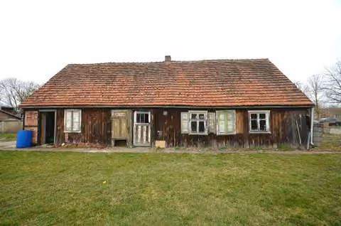 Zwangsversteigerung Einfamilienhaus in Dreetz – Fassadenansicht mit Terrasse und Fassadenschäden.