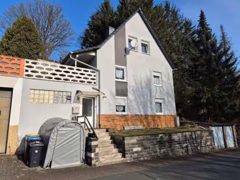 Zwangsversteigerung Einfamilienhaus in Breidenbach, Oberdieten – Vorderansicht des Einfamilienhauses von der Schmidtrainstraße mit Hauseingang.