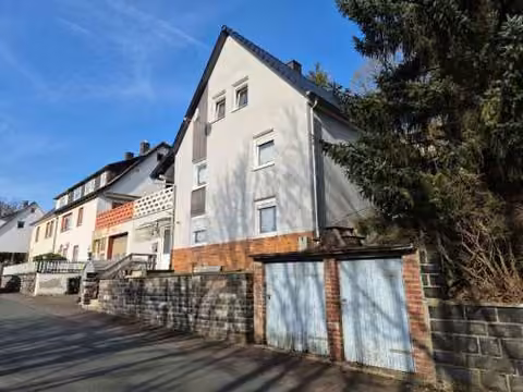 Zwangsversteigerung Einfamilienhaus in Breidenbach, Oberdieten – Straßenansicht des Wohnhauses aus seitlicher Perspektive.