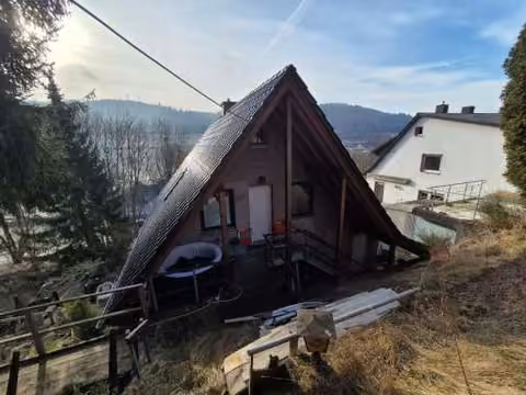 Zwangsversteigerung Einfamilienhaus in Breidenbach, Oberdieten – Rückansicht des Einfamilienhauses am Hang mit Giebel.