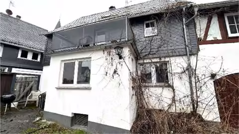 Zwangsversteigerung Wohn-/Geschäftshaus in Eschenburg, Simmersbach – Außenansicht der Fassade des Wohnhauses mit Balkon.