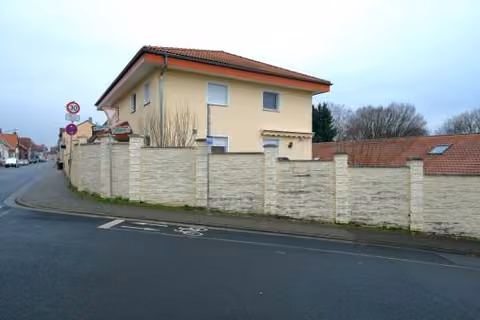 Zwangsversteigerung Zweifamilienhaus in Karben, Rendel – Nordwestliche Gebäudeecke mit massiver Einfriedungsmauer.