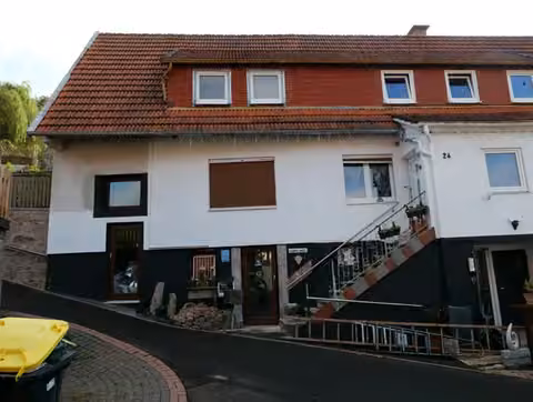 Zwangsversteigerung Einfamilienhaus in Gersfeld, Hettenhausen – Eingangsbereich und Treppenaufgang an der Fassade.
