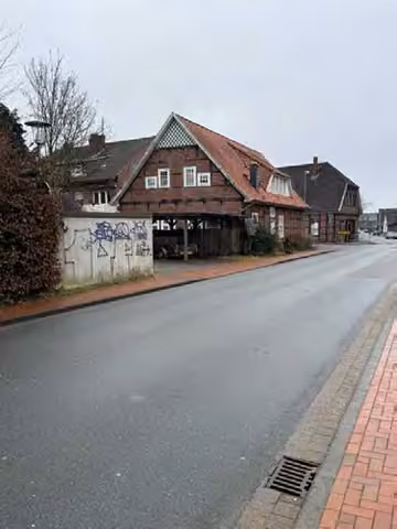 Zwangsversteigerung Einfamilienhaus in Quakenbrück – Straßenansicht Nord-West des Wohnhauses an der Straßenkreuzung.