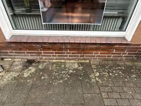 Zwangsversteigerung Einfamilienhaus in Quakenbrück – Detailaufnahme des schadhaften Sockelbereichs unterhalb des Fensters.