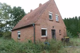 Zwangsversteigerung Einfamilienhaus in Friesoythe, Altenoythe – Schrägansicht des freistehenden Einfamilienhauses mit Ziegelfassade und Satteldach.