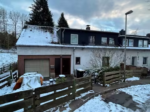 Zwangsversteigerung Reihenhaus in Porta Westfalica, Hausberge – Nordansicht des Einfamilien-Reihenendhauses mit Garage von der Straße aus.