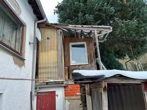 Zwangsversteigerung Reihenhaus in Porta Westfalica, Hausberge – Westansicht des ungenehmigten Holz-Anbaus am Gebäude.