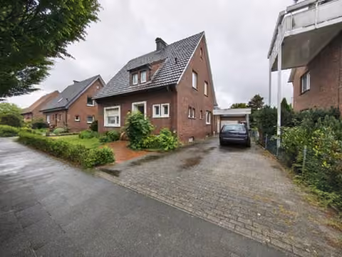 Zwangsversteigerung Einfamilienhaus in Harsewinkel, Marienfeld – Straßenansicht des freistehenden Einfamilienhauses mit Zufahrt und Vorgarten.