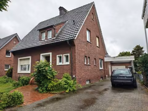 Zwangsversteigerung Einfamilienhaus in Harsewinkel, Marienfeld – Ansicht der Giebelseite mit Klinkermauerwerk und Garagenzufahrt.