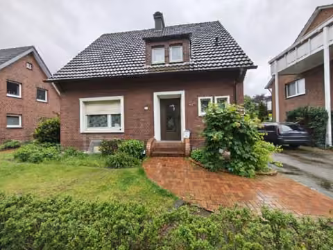 Zwangsversteigerung Einfamilienhaus in Harsewinkel, Marienfeld – Frontansicht mit Hauseingangsbereich und Vorgartenbepflanzung.
