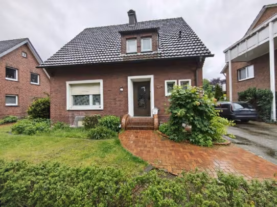 Zwangsversteigerung Einfamilienhaus in Harsewinkel, Marienfeld – Frontansicht mit Hauseingangsbereich und Vorgartenbepflanzung.