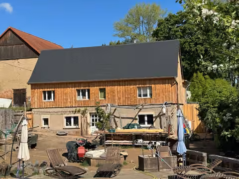Zwangsversteigerung Einfamilienhaus in Reinsberg, Bieberstein – Außenansicht des Wohnhauses mit Gartenbereich und Holzverschalung.