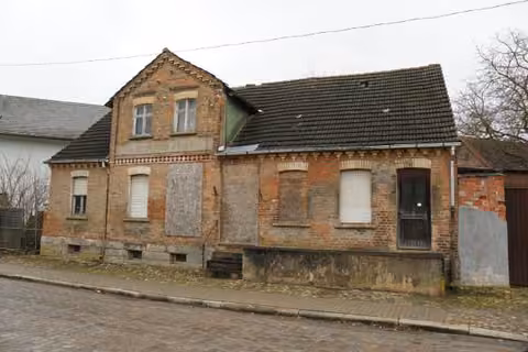 Zwangsversteigerung Einfamilienhaus in Oschersleben, Hornhausen – Straßenseitige Außenansicht des verfallenen Wohn- und Geschäftshauses.