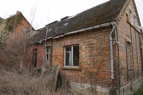 Zwangsversteigerung Einfamilienhaus in Oschersleben, Hornhausen – Rückwärtige Außenansicht mit sichtbaren Dach- und Bauschäden.