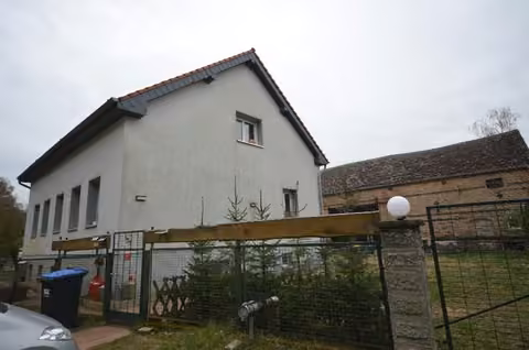 Zwangsversteigerung Einfamilienhaus in Kremmen, Hohenbruch – Seitliche Ansicht des Wohnhauses mit Blick auf den Hof und die Einfriedung.