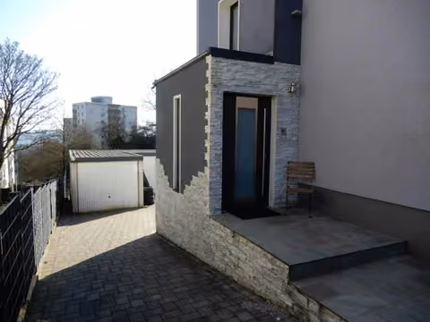 Zwangsversteigerung Einfamilienhaus in Wuppertal, Nächstebreck – Hauseingangsbereich mit Klinkerverblendung und Blick auf die Garagen.
