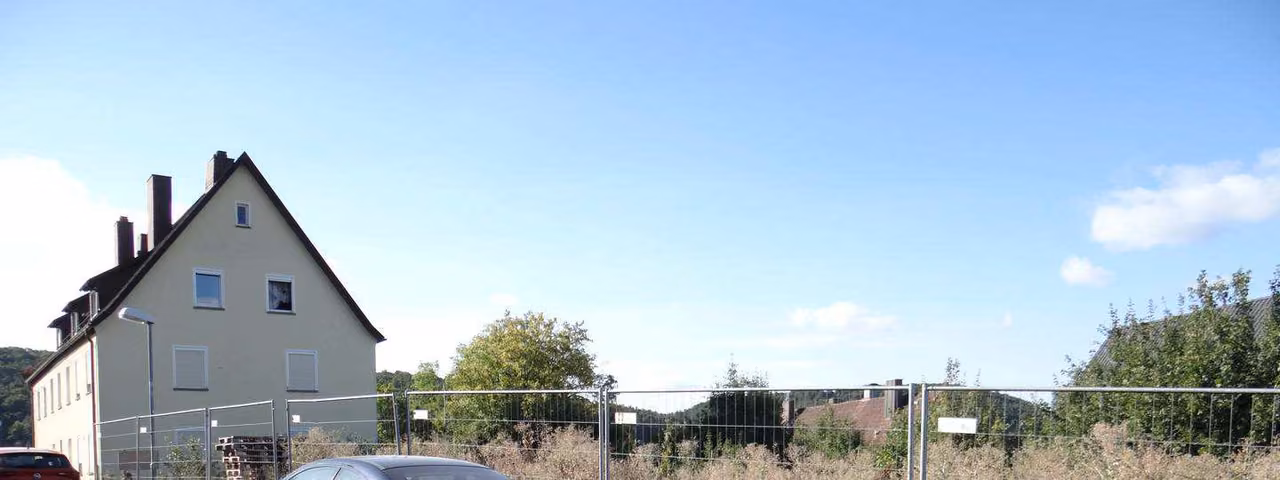 Zwangsversteigerung Grundstück in Bad Kissingen – Blick auf das unbebaute Grundstück von Norden mit Baustellenabsperrung.