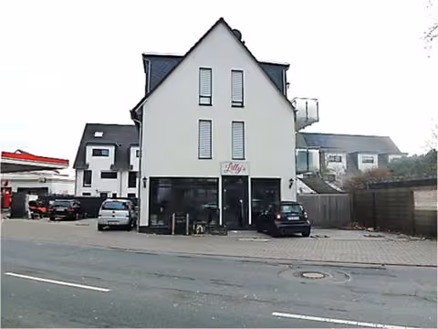Zwangsversteigerung Einfamilienhaus in Raunheim – Seitenansicht des Gebäudes mit Pkw-Stellplätzen.